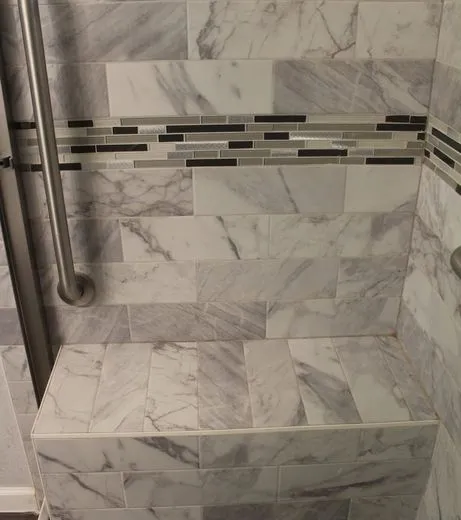 Finished marble-look tile shower with a built-in bench and grab bar