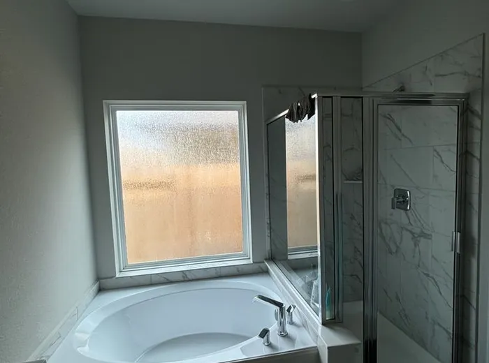 Completed primary bathroom remodel with soaking tub and frameless glass shower