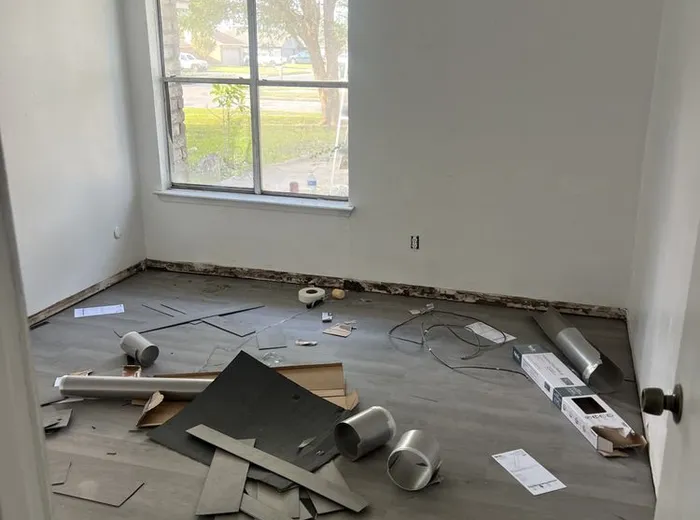 Room with old flooring removed and new plank flooring staged for installation