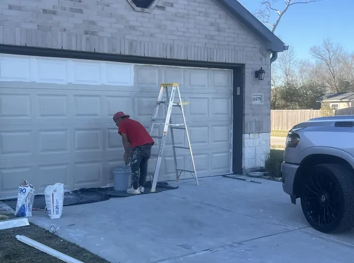 Contractor painting a garage door from a ladder