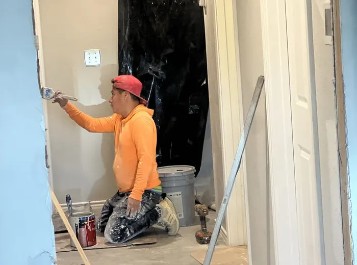 Painter rolling primer on an interior wall during a renovation