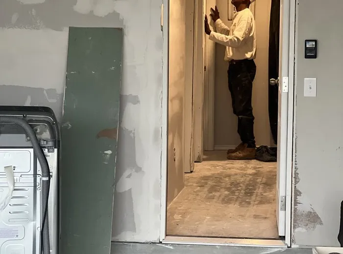 Crew member inspecting a room mid-remodel with patched drywall