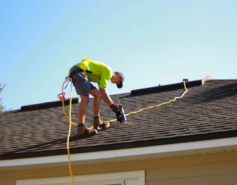 Roofer using a drill during a shingle roof repair